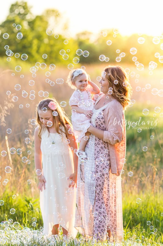 Mother with two children in field with bubbles