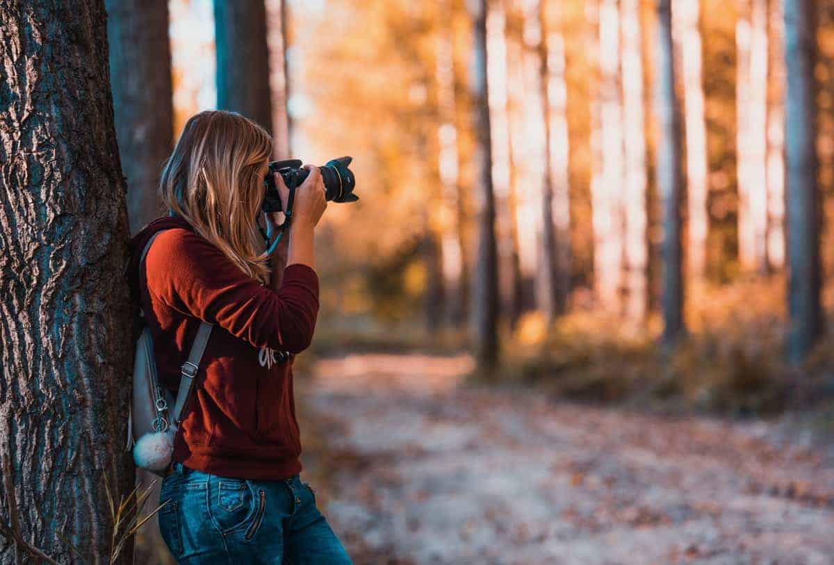 Girl taking a photograph in the woods