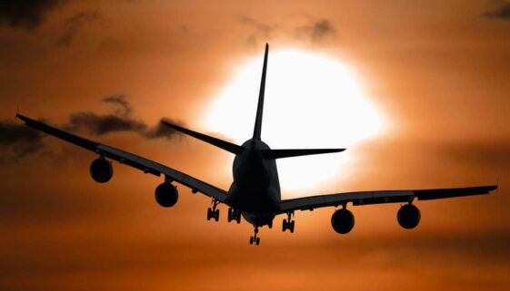 airplane flying towards sunset