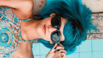 girl with blue hair and sunglasses laying down