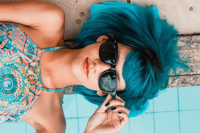girl with blue hair and sunglasses laying down