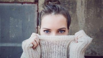 woman holding sweater over her nose