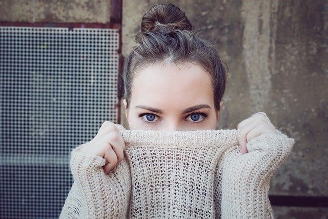 woman holding sweater over her nose
