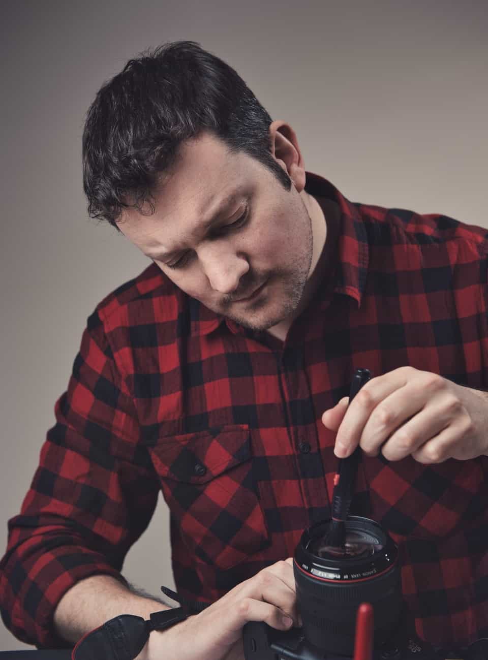 man in plaid shirt cleaning camera lens