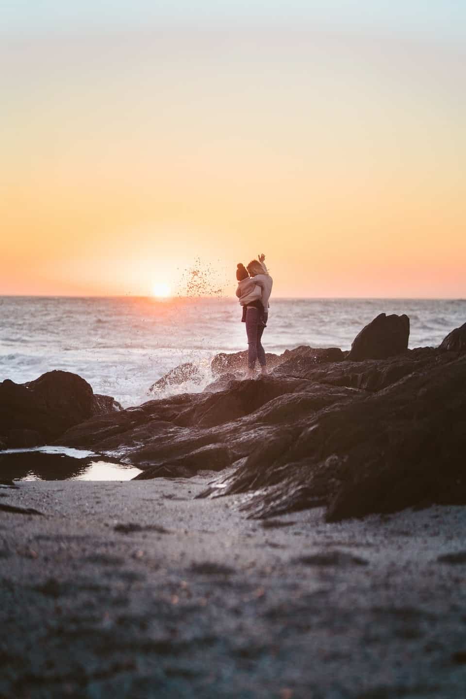 mother with child on rocks looking at sunset