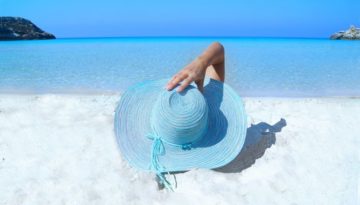 woman laying on the beach with blue hat