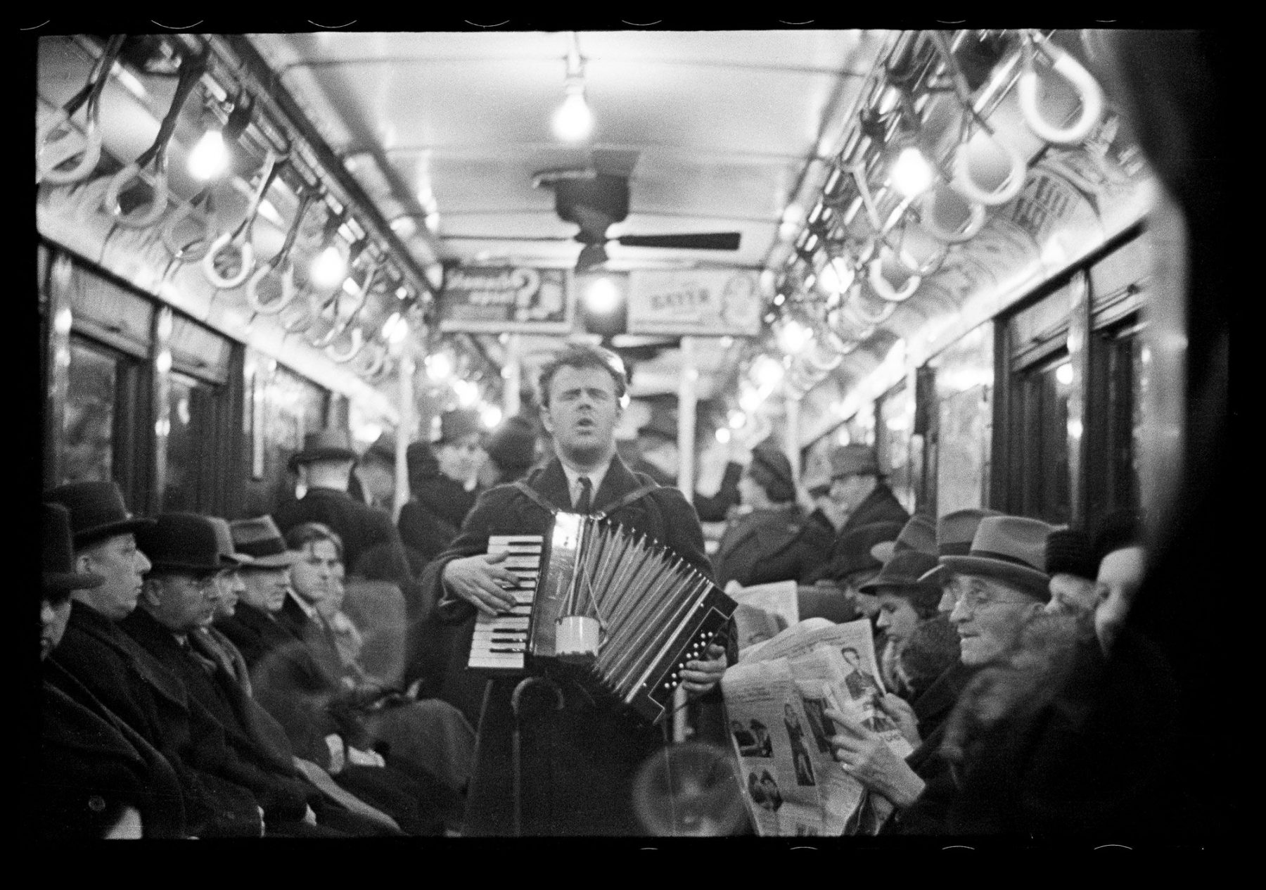 black and white photo of man playing accordion in subway