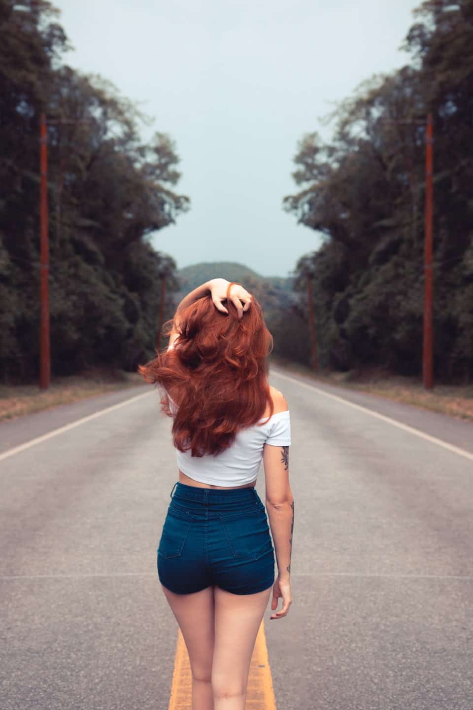 woman with red hair walking down road with back turned away from the camera