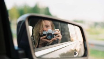 girl in rearview mirror holding camera
