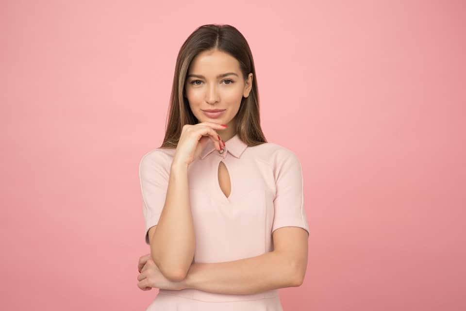 woman in pink dress posed against pink backdrop