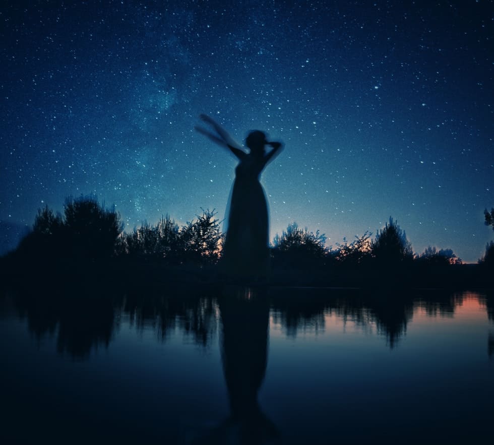 silhouette of woman in front of star filled sky